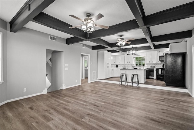 unfurnished living room featuring visible vents, light wood-type flooring, a ceiling fan, and baseboards