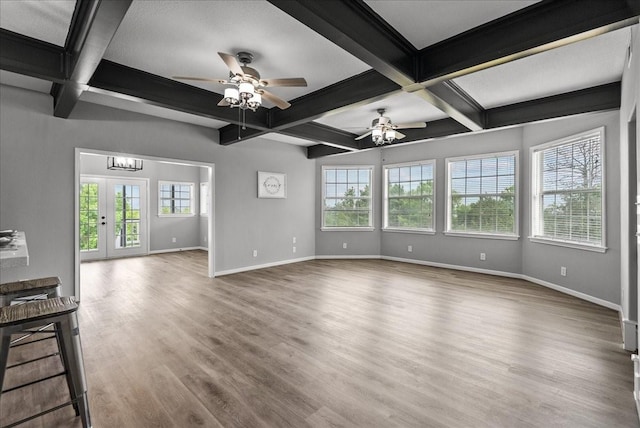 unfurnished living room featuring baseboards, ceiling fan with notable chandelier, and coffered ceiling