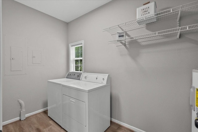 clothes washing area with baseboards, washer and dryer, light wood-style floors, and laundry area