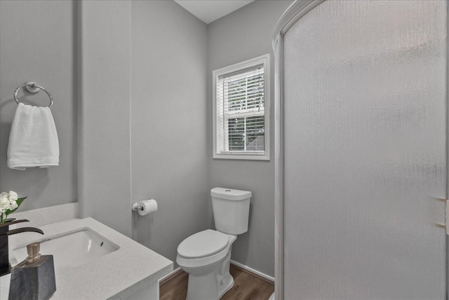 bathroom featuring vanity, wood finished floors, toilet, and an enclosed shower