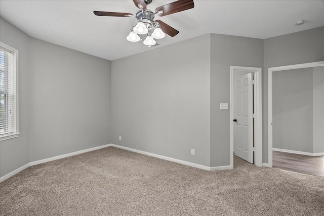 carpeted spare room with a ceiling fan and baseboards