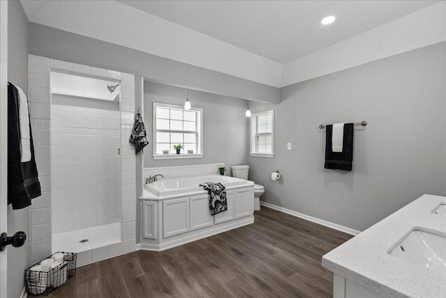 bathroom featuring a bath, toilet, baseboards, walk in shower, and wood finished floors