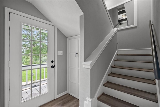 interior space with baseboards, stairway, wood finished floors, and vaulted ceiling