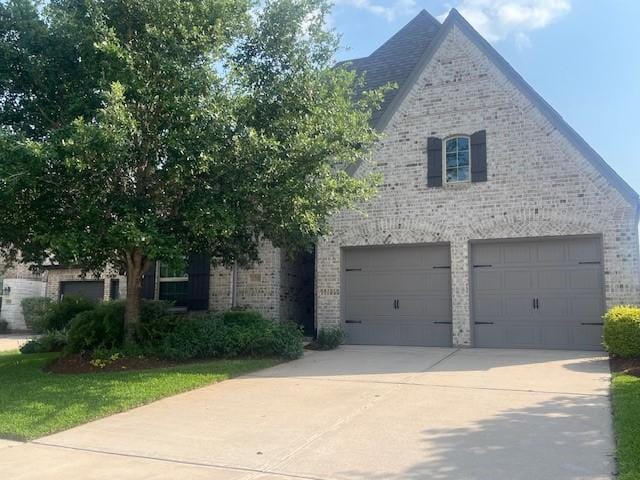 obstructed view of property with an attached garage, driveway, and brick siding