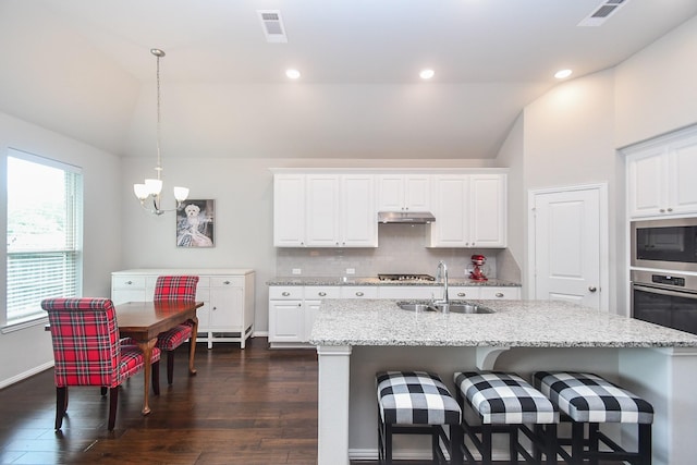 kitchen featuring appliances with stainless steel finishes, an inviting chandelier, a sink, under cabinet range hood, and vaulted ceiling