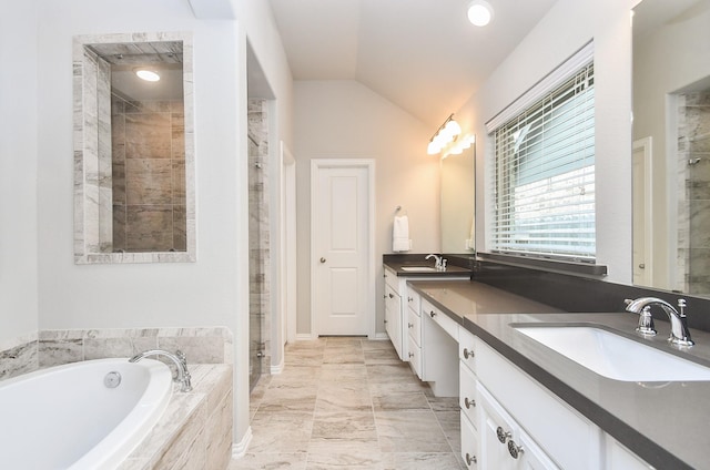 bathroom with vaulted ceiling, a sink, a garden tub, and a stall shower