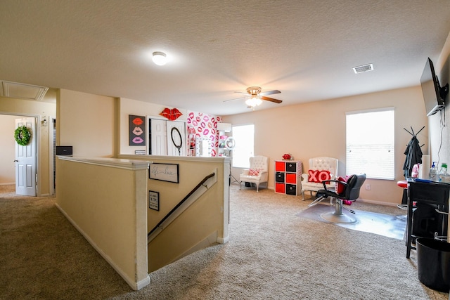 interior space with carpet flooring, an upstairs landing, visible vents, attic access, and a wealth of natural light