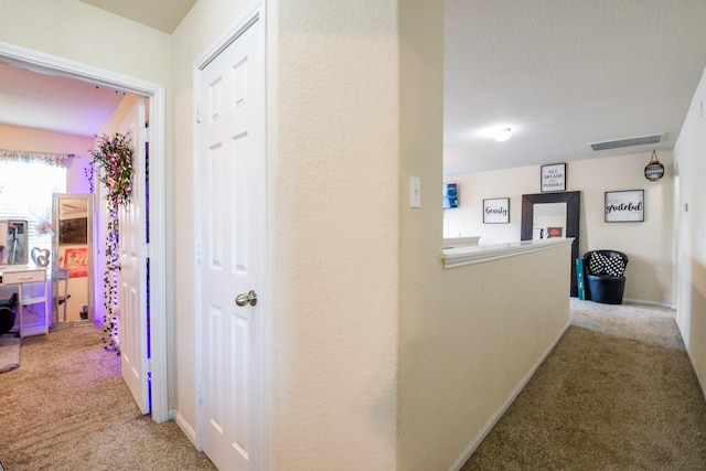 corridor with baseboards, visible vents, and carpet