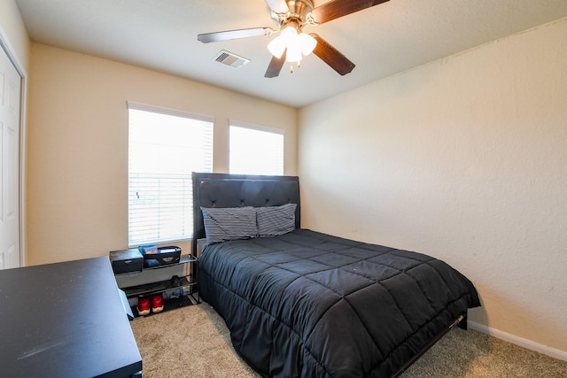 carpeted bedroom featuring a ceiling fan, visible vents, and baseboards