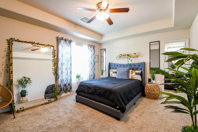 bedroom with carpet, baseboards, visible vents, a ceiling fan, and a tray ceiling