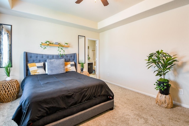 carpeted bedroom featuring ensuite bathroom, a ceiling fan, baseboards, and a tray ceiling