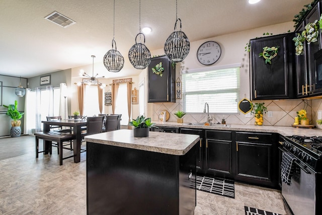 kitchen with dark cabinets, a sink, black gas stove, visible vents, and a center island