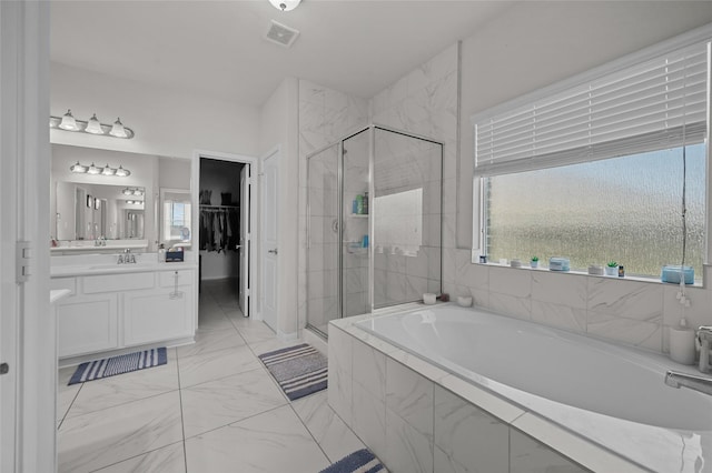full bathroom with vanity, a stall shower, a bath, a wealth of natural light, and a spacious closet