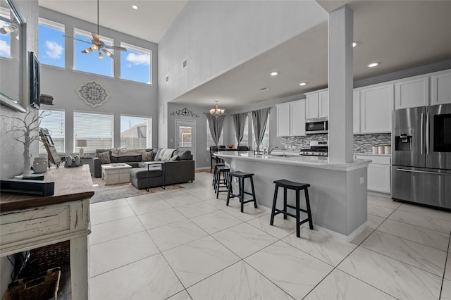 kitchen with an inviting chandelier, a breakfast bar area, stainless steel appliances, light countertops, and a high ceiling