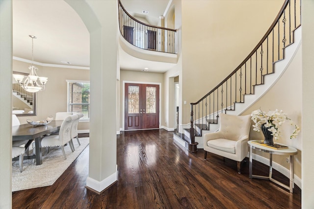 foyer featuring french doors, arched walkways, wood finished floors, baseboards, and stairs