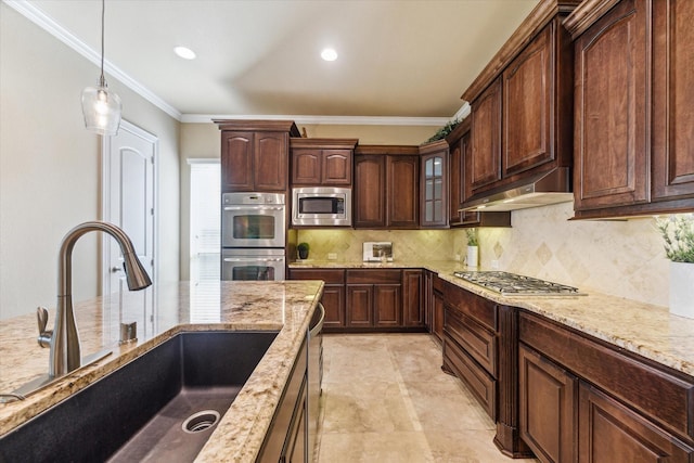 kitchen with crown molding, a sink, stainless steel appliances, under cabinet range hood, and pendant lighting