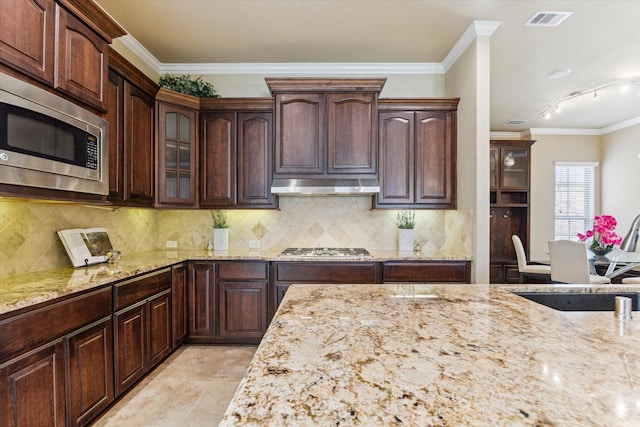 kitchen with appliances with stainless steel finishes, light stone countertops, under cabinet range hood, and visible vents