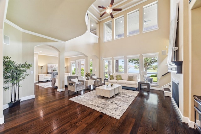 living room featuring arched walkways, a fireplace, a ceiling fan, and dark wood-style flooring