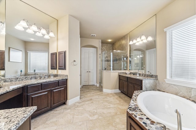 bathroom featuring two vanities, a shower stall, a healthy amount of sunlight, and a garden tub