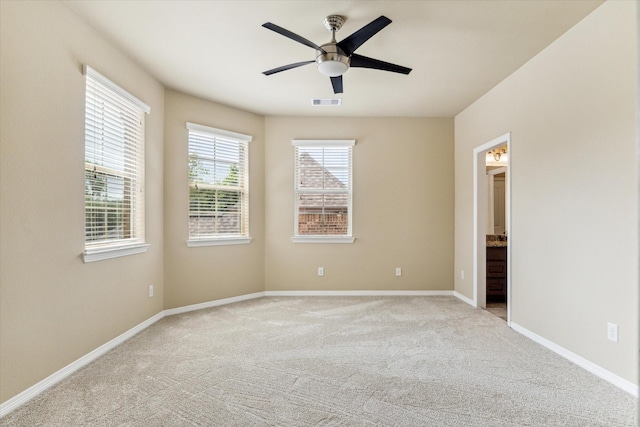unfurnished bedroom with baseboards, light carpet, connected bathroom, and visible vents