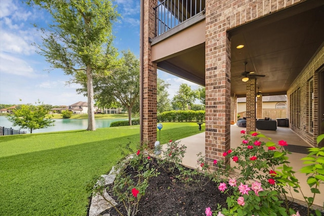 view of yard with a ceiling fan, a patio, a water view, and a balcony