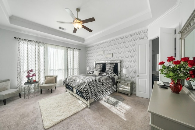 bedroom with carpet flooring, ceiling fan, a tray ceiling, visible vents, and ornamental molding