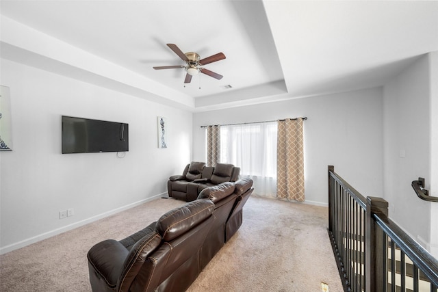 carpeted living room featuring a tray ceiling, ceiling fan, visible vents, and baseboards