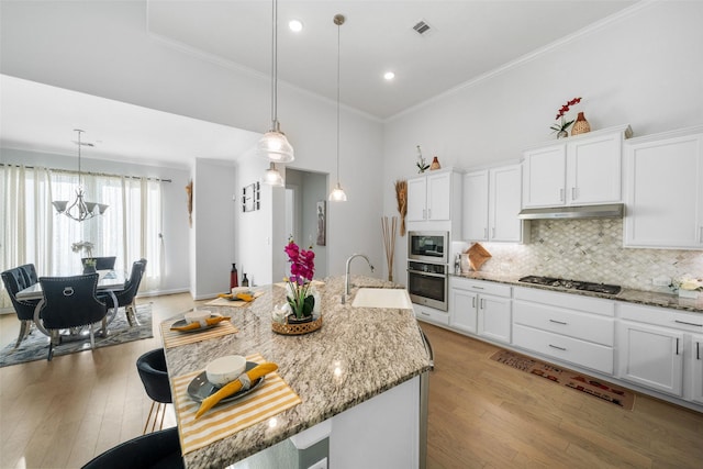 kitchen with a sink, stainless steel appliances, light wood-type flooring, white cabinetry, and ornamental molding