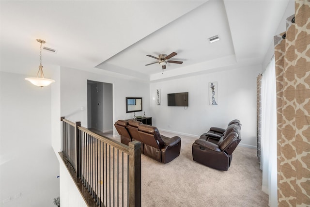 carpeted living room featuring a raised ceiling, ceiling fan, visible vents, and baseboards