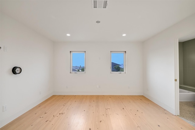 empty room featuring recessed lighting, visible vents, hardwood / wood-style floors, and baseboards