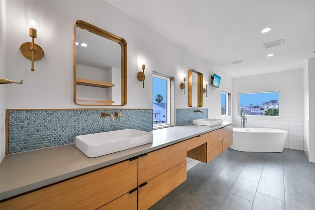 full bath with tile patterned flooring, double vanity, a sink, and a freestanding bath