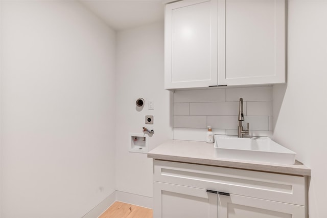 washroom featuring hookup for an electric dryer, a sink, cabinet space, hookup for a washing machine, and wood finished floors