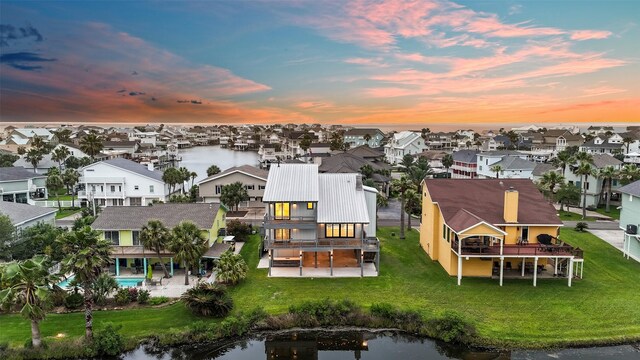 aerial view at dusk with a residential view and a water view