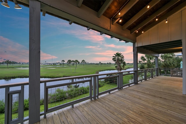 deck at dusk featuring a water view