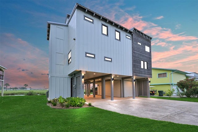 view of front of home with concrete driveway, a carport, a yard, and board and batten siding