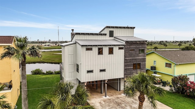 exterior space featuring concrete driveway, a carport, a water view, and central AC