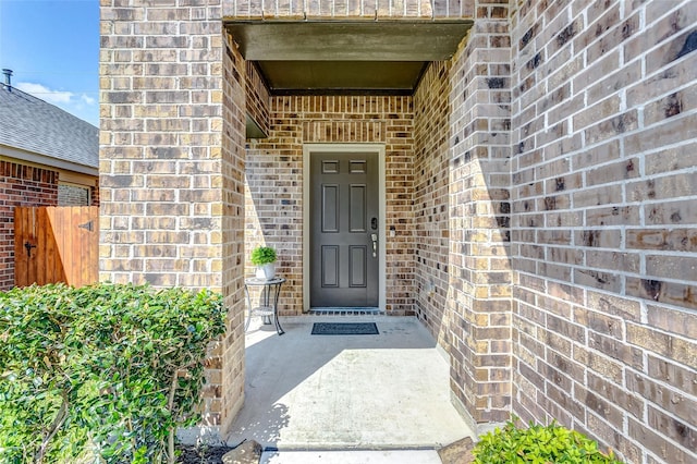 doorway to property with fence and brick siding
