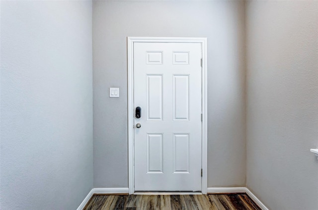 doorway with baseboards and dark wood-style flooring