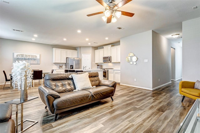 living room with visible vents, ceiling fan, light wood-style floors, baseboards, and recessed lighting
