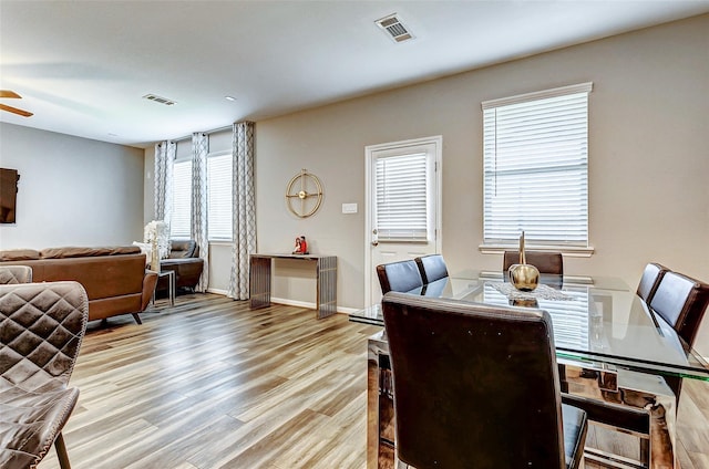 dining room with visible vents, wood finished floors, ceiling fan, and plenty of natural light