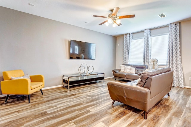 living room featuring visible vents, light wood-style flooring, and baseboards