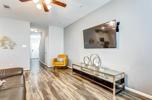 living room with wood finished floors, visible vents, a ceiling fan, and baseboards