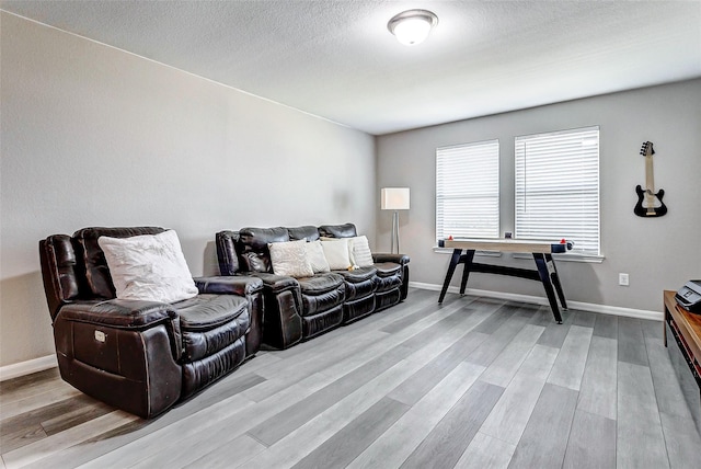 living area with light wood finished floors, a textured ceiling, and baseboards