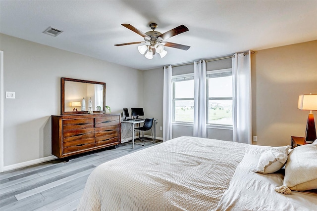 bedroom featuring a ceiling fan, visible vents, baseboards, and light wood-type flooring