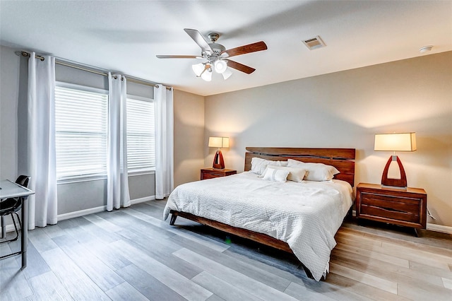bedroom featuring visible vents, ceiling fan, light wood-style floors, and baseboards