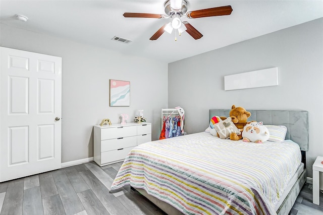 bedroom featuring a ceiling fan, visible vents, light wood-style flooring, and baseboards