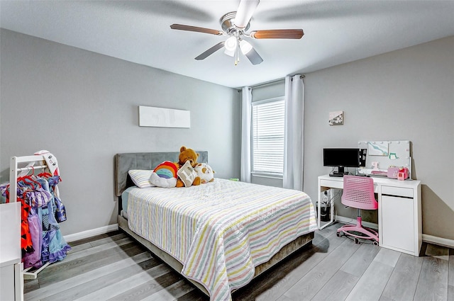 bedroom with ceiling fan, baseboards, and light wood-type flooring