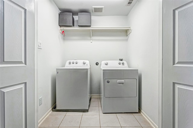 clothes washing area with light tile patterned floors, washing machine and dryer, visible vents, baseboards, and laundry area