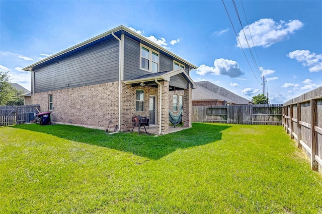 rear view of house featuring a lawn, a patio, brick siding, and a fenced backyard