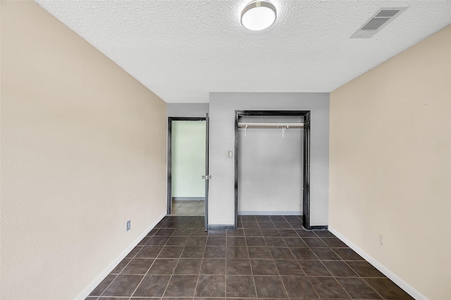 20983 Westgrove Ln, Porter, TX 77365 - unfurnished bedroom featuring dark tile patterned floors, a closet, a textured ceiling, visible vents, and baseboards